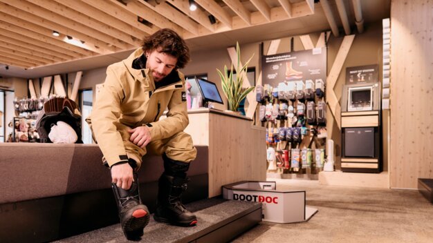 Man trying on snowboard boots in a store. | © ARMIN WALCHER