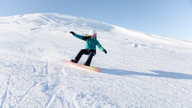 Woman snowboarding down a snowy slope. | © Rossignol
