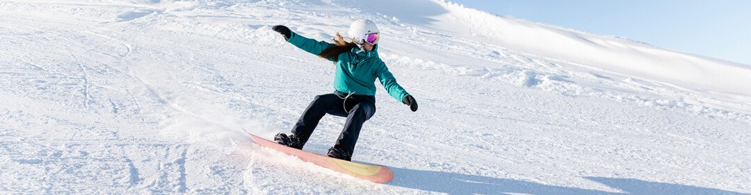 Woman snowboarding down a snowy slope. | © Rossignol