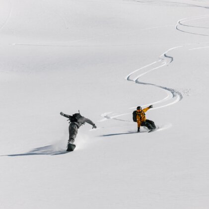 Two snowboarders riding down a snowy slope. | © Salomon
