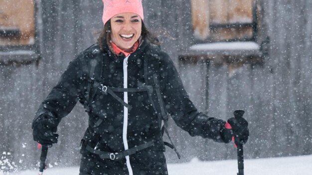 Woman snowshoeing and smiling in snowfall. | © IIC/McKINLEY
