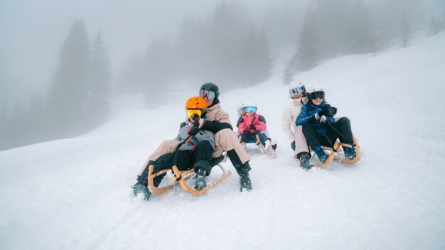 Famille faisant de la luge sur une colline enneigée.