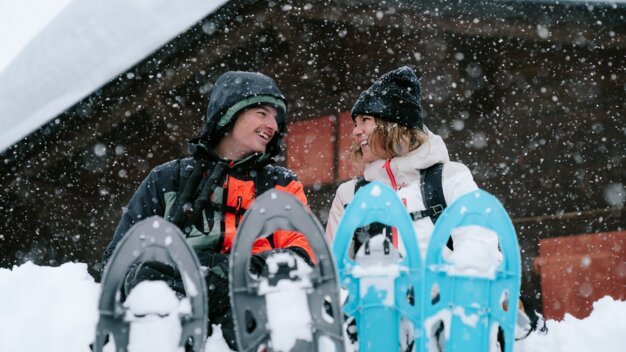 Deux personnes avec des raquettes à neige dans la neige.