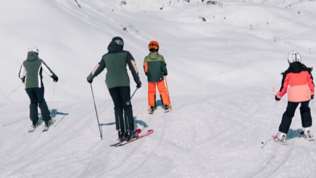 Four people skiing down a ski slope.