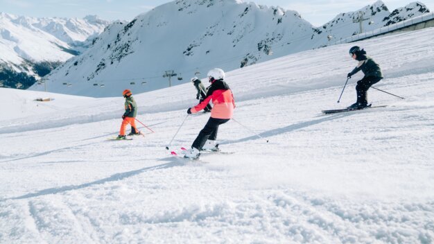 Skieurs sur une pente enneigée avec des montagnes en arrière-plan