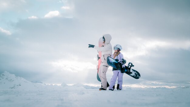 Two snowboarders standing on a snowy mountain.