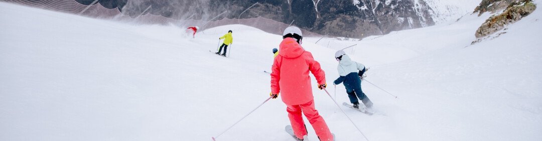 Skiers on a snowy slope with mountains in the background.