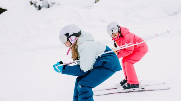 Two girls skiing in the snow.