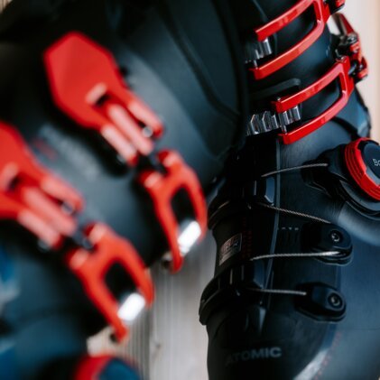 Close-up of black ski boots with red buckles and a BOA system.