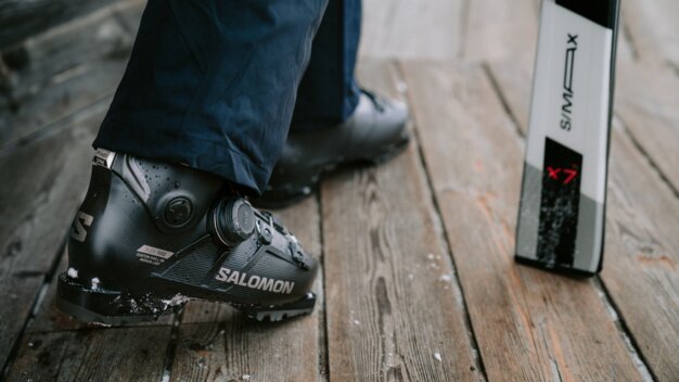 Salomon ski boot with a ski in the background.