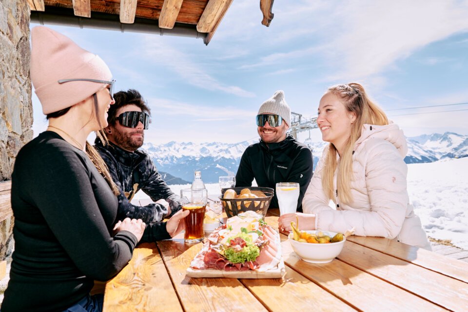 Gruppe von Freunden isst auf einer Skihütte. | © ARMIN WALCHER