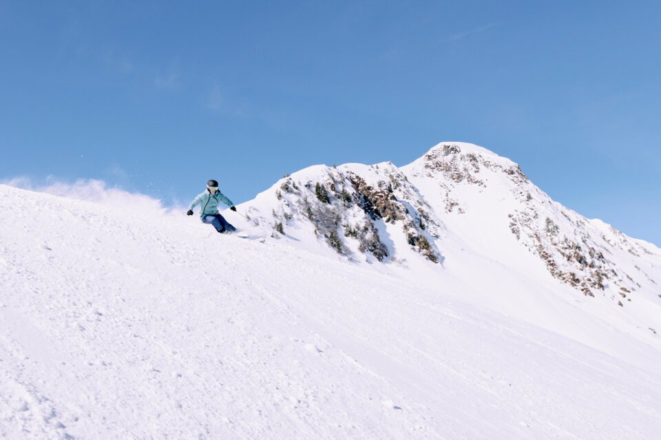 Skifahrerin auf schneebedecktem Hang unter blauem Himmel. | © ARMIN WALCHER