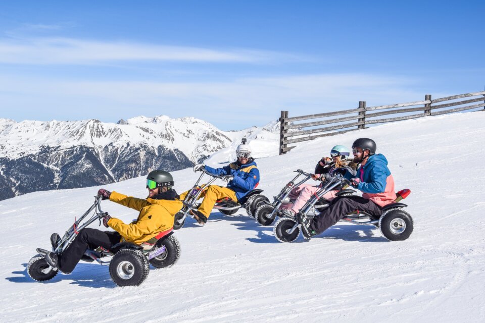 Gruppe fährt mit Mountainkarts auf einer schneebedeckten Piste. | © Serre Chevalier Vallée Brianҫon / @laurapeythieu
