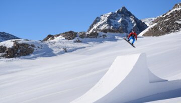 Snowboarder jumping off a ramp in the mountains. | © Serre Chevalier Vallée Brianҫon / @laurapeythieu