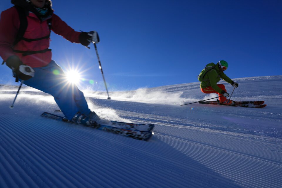 Two skiers skiing on a groomed slope under bright sunlight. | © OT Flaine-Monica Dalmasso_flaine3ot-flaine-monica-dalmasso-5d6f816401226