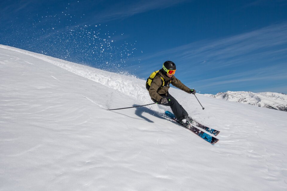 Skier carving through powder on a sunny day. | © J. Kelagopian OTM NCA