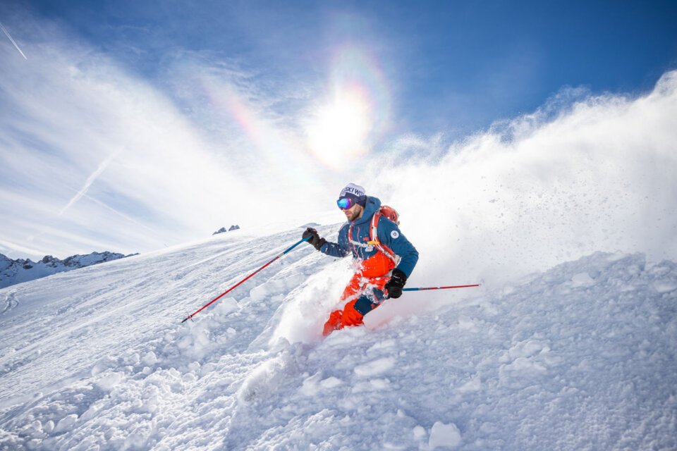 Skier riding powder on a sunny day. | © Courchevel Tourisme