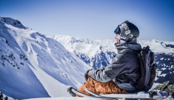 Skier sits on top of a snowy mountain while looking out at the landscape. | © Les Arcs Wearemerci