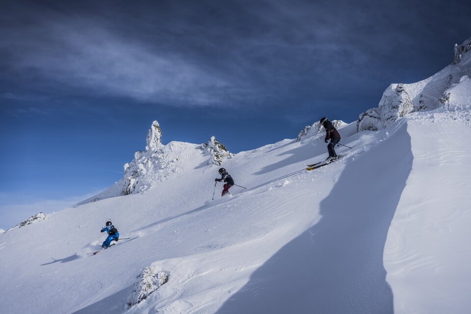 Three skiers descending a snowy mountain slope. | © Les Arcs Wearemerci