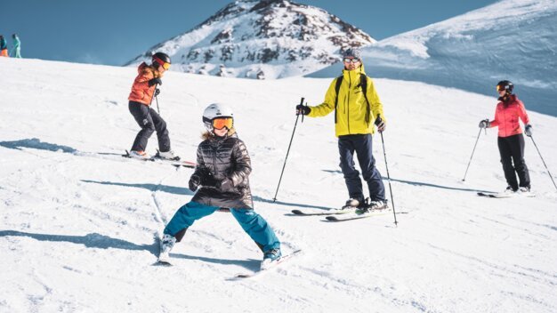 Skiers on a ski slope with snow-covered mountains in the background. | © Les 2 Alpes / Luka Leroy