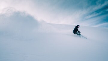 Snowboarder descendant une pente enneigée.