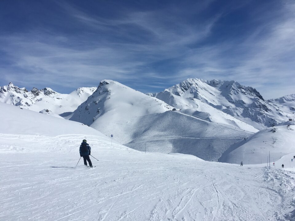 Skier on snowy slope with mountain range.