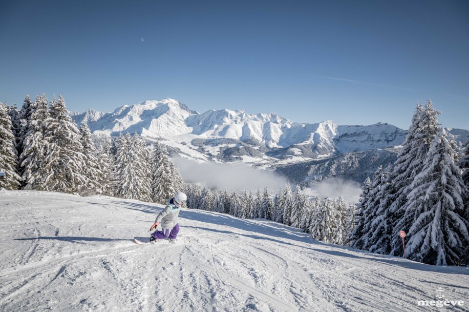 Snowboarderin auf schneebedeckter Piste mit Bergpanorama | © Simon Garnier