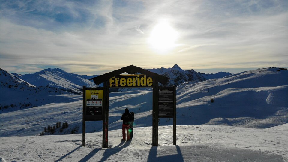 A skier stands before a Freeride sign in a snowy mountain landscape. | © Florian COLAS / Office de Tourisme de Montgenèvre