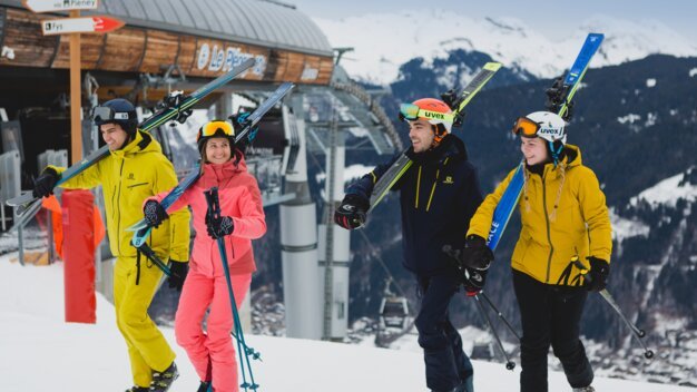 A group of four skiers walking in the snow with their skis over their shoulders. | © Morzine Tourist Office