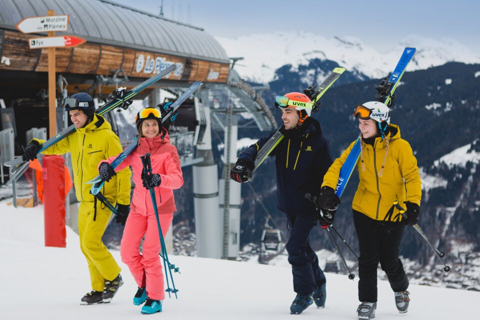 A group of four skiers walking in the snow with their skis over their shoulders. | © Morzine Tourist Office