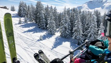 Skieurs sur un télésiège avec vue sur des arbres enneigés et des montagnes. | © Morzine Tourist Office