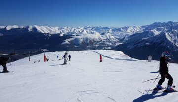 Skier on a snowy slope with mountains in the background. | © OT Saint Lary