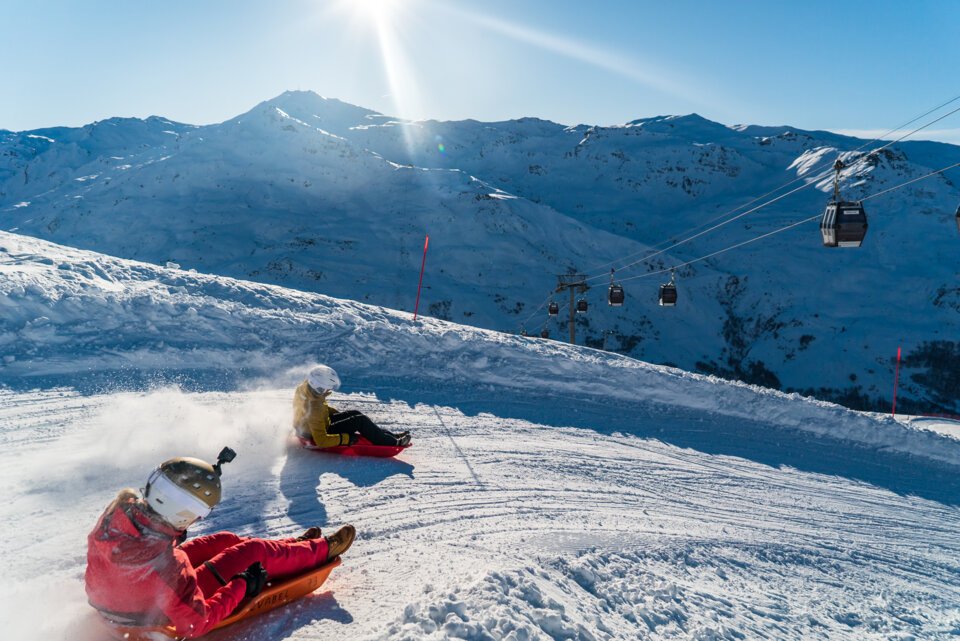 Two people sledding down a snowy slope. | © Vincent LOTTENBERG