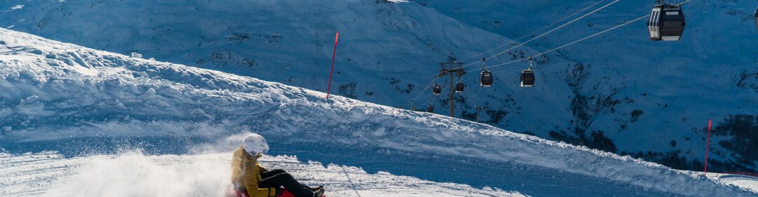 Deux personnes font de la luge sur une pente enneigée. | © Vincent LOTTENBERG
