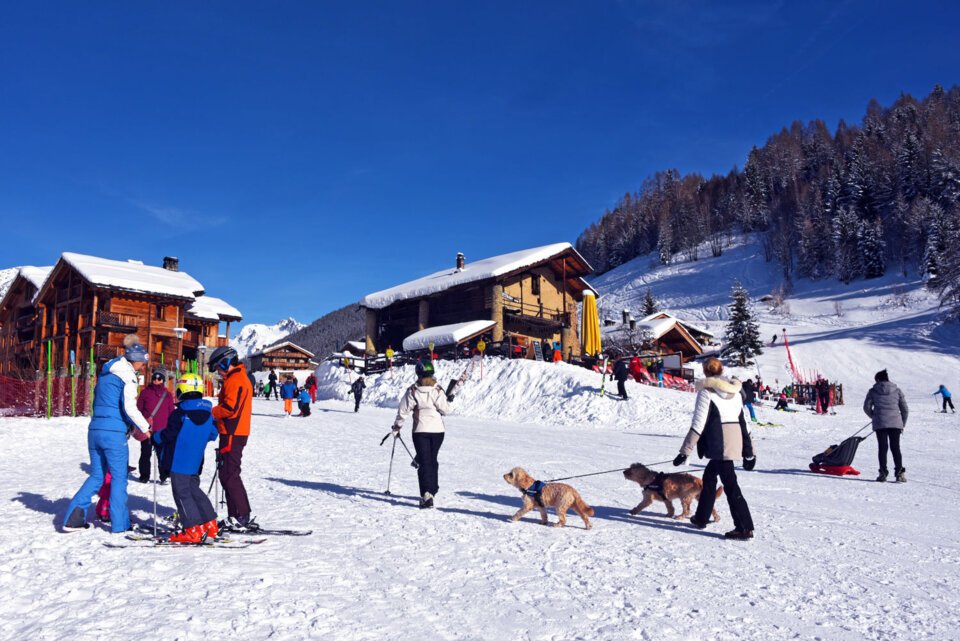 Station de ski avec des personnes, des bâtiments et des chiens dans la neige. | © Philippe Royer / Sainte Foy Tourisme