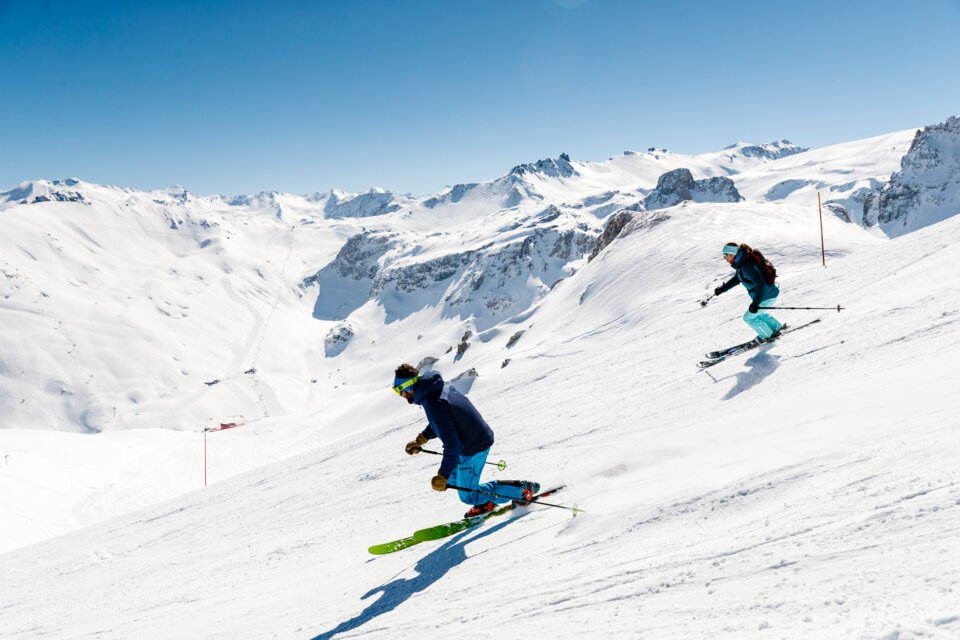 Zwei Skifahrer auf schneebedeckter Piste vor Bergkulisse. | © Stephane Cande / Tignes