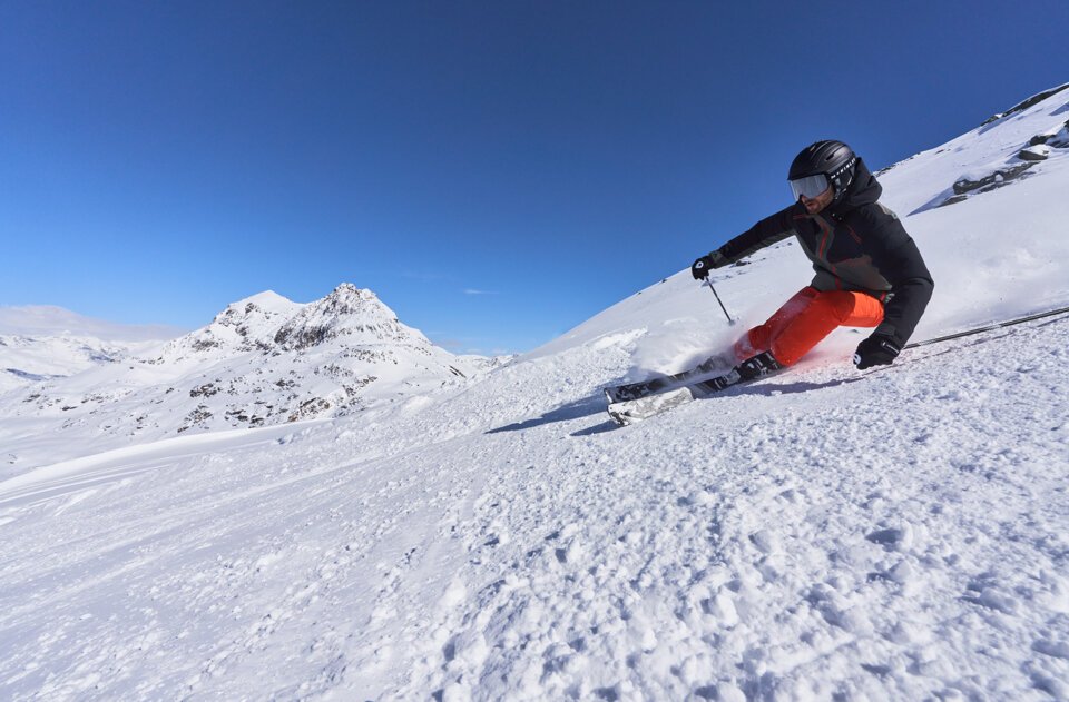 Skifahrer fährt auf schneebedecktem Hang ab.