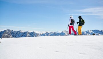 Two ski tourers on a snow-covered summit.