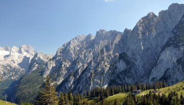 Paysage de montagne avec des pentes boisées et des sommets enneigés | © info@dachstein.at 