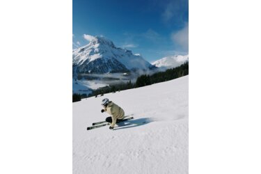 Skier on a snowy slope with mountain backdrop.