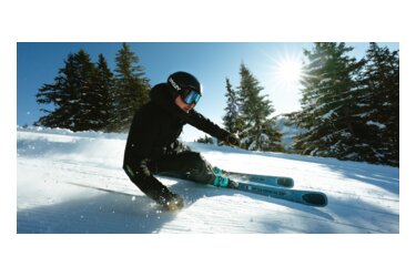 Skier in black clothing skiing on a snowy slope.