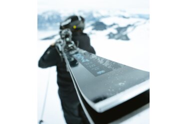 Person with skis on shoulder in snow.