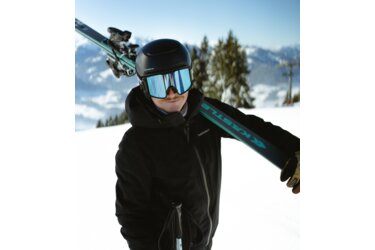 Skifahrer mit Skiern und Helm auf der Schulter.