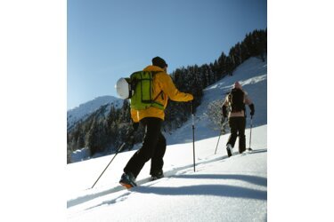 Two people ski touring in the snow.