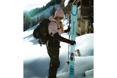 Frau mit Skiern und Rucksack im Schnee