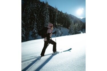 Frau beim Skitourengehen in verschneiter Landschaft