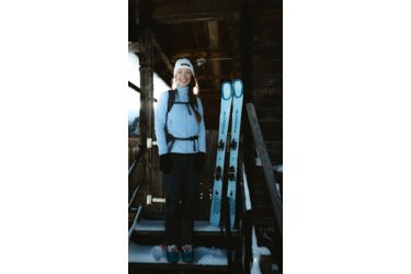 Femme en équipement de ski se tenant sur des marches enneigées.