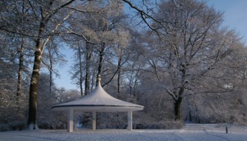 Schneebedeckter Park mit Pavillon und Bäumen. | © www.wikipedia.com