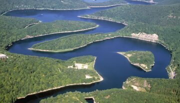 Aerial view of a winding waterway through forested hills. | © Archiv Eifel Tourismus GmbH / Nationalpark Eifel