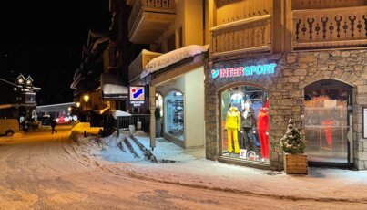 Intersport shop on a snowy street at night.